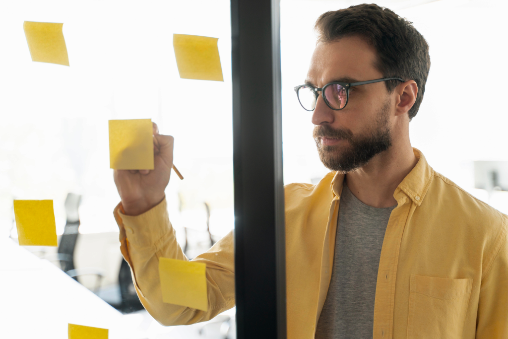 A senior strategist working with notes on a glass wall